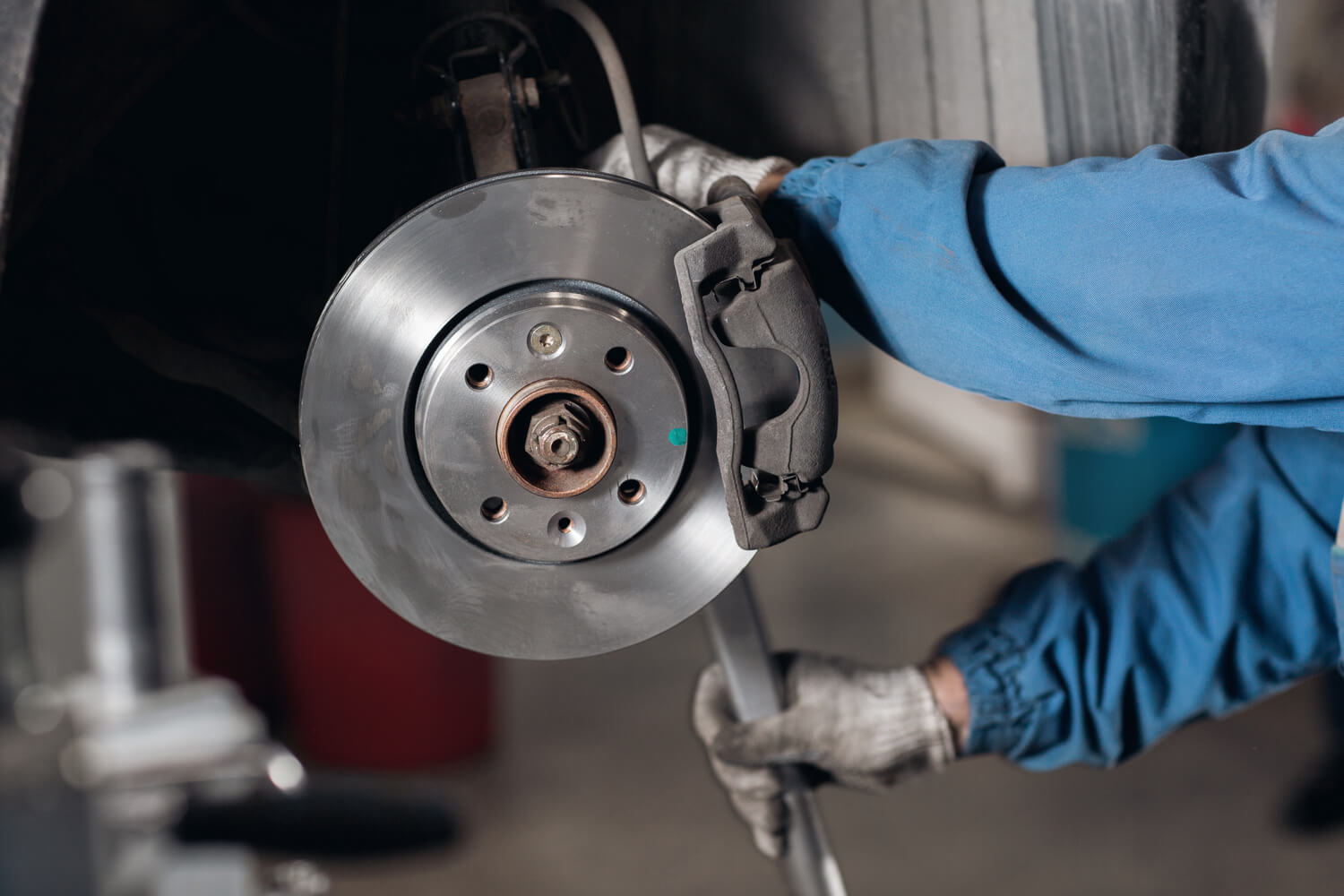 change the old drive to the Brand new brake disc on car in a garage. Auto mechanic repairing .